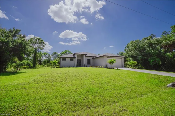 View of front of home with a garage and a front lawn