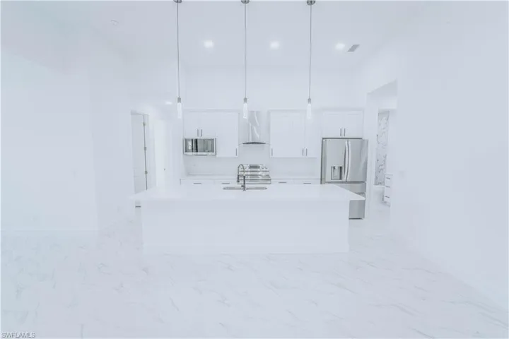 Kitchen with pendant lighting, stainless steel appliances, a center island with sink, and light tile patterned floors