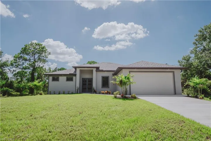 View of front facade featuring a garage and a front lawn