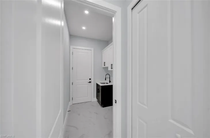 Laundry room featuring recessed lighting and light marble finish flooring