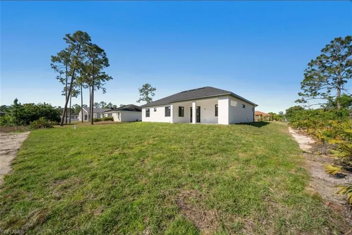 Rear view of property with a yard and stucco siding
