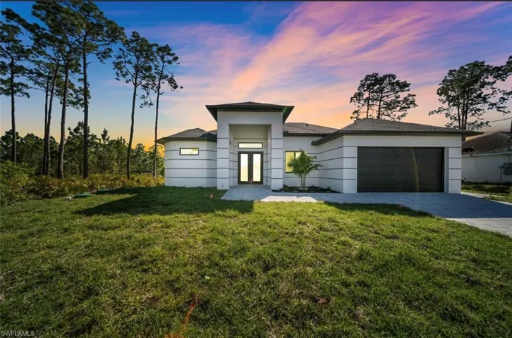 Prairie-style home with a yard, a garage, driveway, french doors, and stucco siding