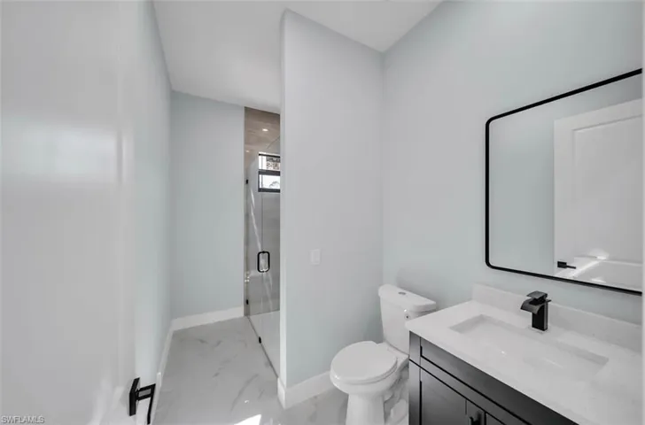 Full bathroom featuring light marble finish floors, vanity, and a shower stall