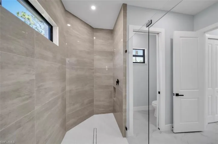 Full bathroom featuring walk in shower, marble look tile flooring, and recessed lighting