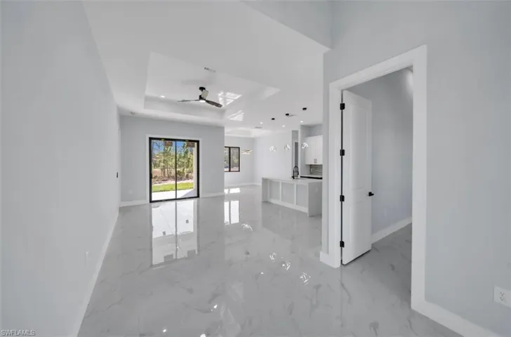 Spare room featuring a tray ceiling, light marble finish flooring, a skylight, recessed lighting, and a ceiling fan