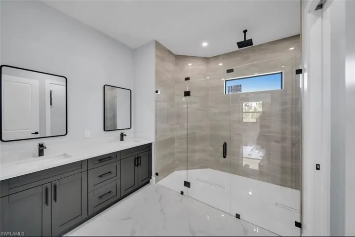 Bathroom featuring double vanity, a stall shower, recessed lighting, and light marble finish flooring