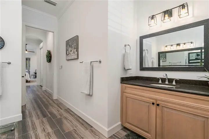 Full bathroom featuring crown molding, vanity, wood finished floors, baseboards, and visible vents