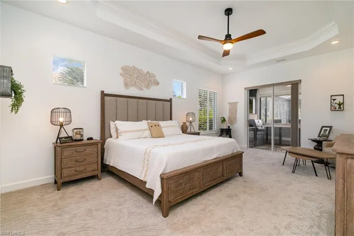 Bedroom featuring a raised ceiling, ornamental molding, access to outside, and light colored carpet
