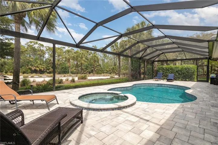 View of pool with a pool with connected hot tub, a lanai, and a patio area