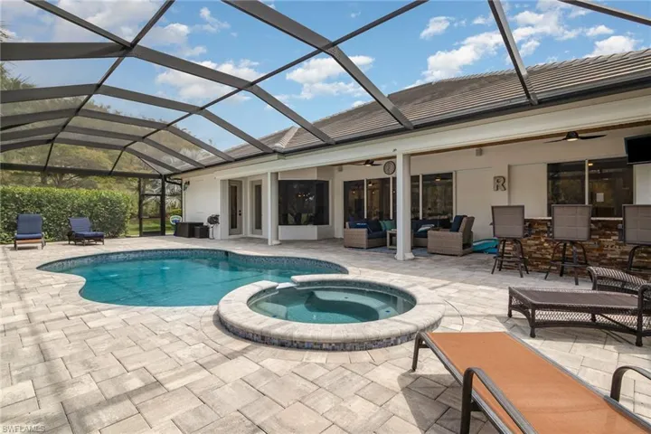 View of pool with a lanai, an outdoor living space, a ceiling fan, a pool with connected hot tub, and a patio area