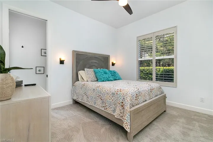 Bedroom featuring light colored carpet, ceiling fan, and baseboards