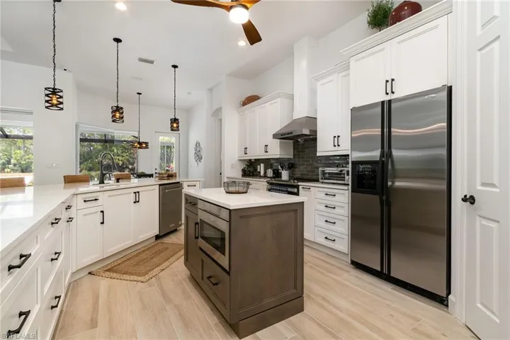 Kitchen with white cabinetry, backsplash, a sink, a ceiling fan, and appliances with stainless steel finishes