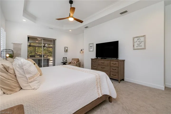 Bedroom with visible vents, crown molding, light carpet, a raised ceiling, and access to exterior