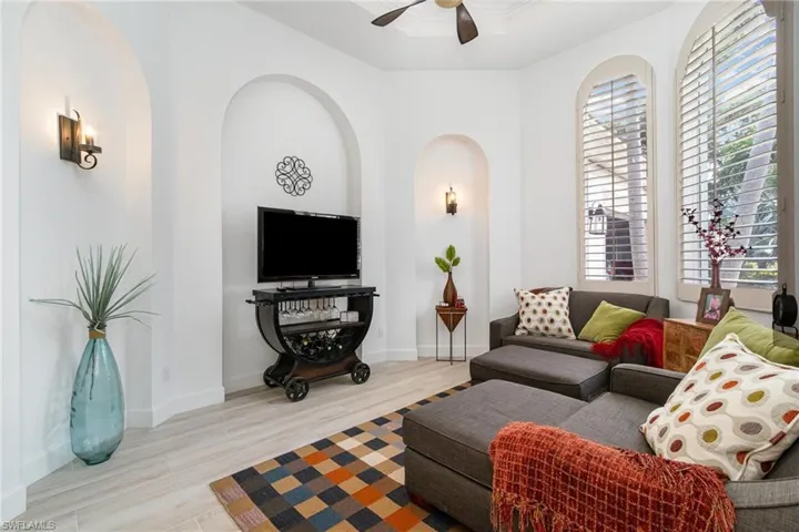 Living area with baseboards, arched walkways, wood finished floors, and a ceiling fan