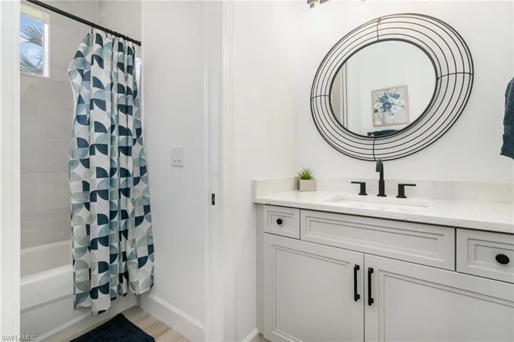Bathroom featuring baseboards, wood finished floors, vanity, and shower / bath combo