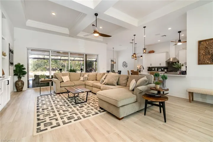 Living area with coffered ceiling, light wood-type flooring, and ceiling fan
