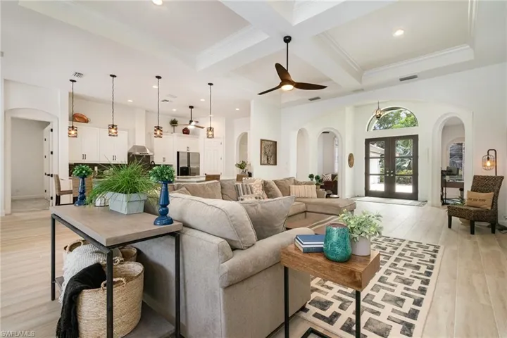 Living area featuring arched walkways, coffered ceiling, beamed ceiling, and light wood finished floors