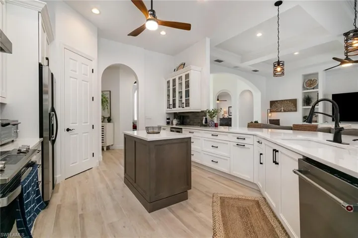 Kitchen with arched walkways, ceiling fan, a sink, and appliances with stainless steel finishes