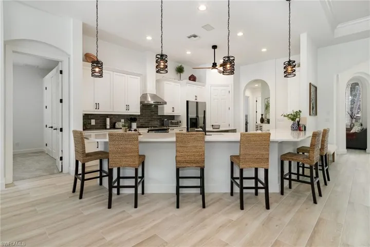 Kitchen with a breakfast bar area, arched walkways, decorative backsplash, and stainless steel fridge