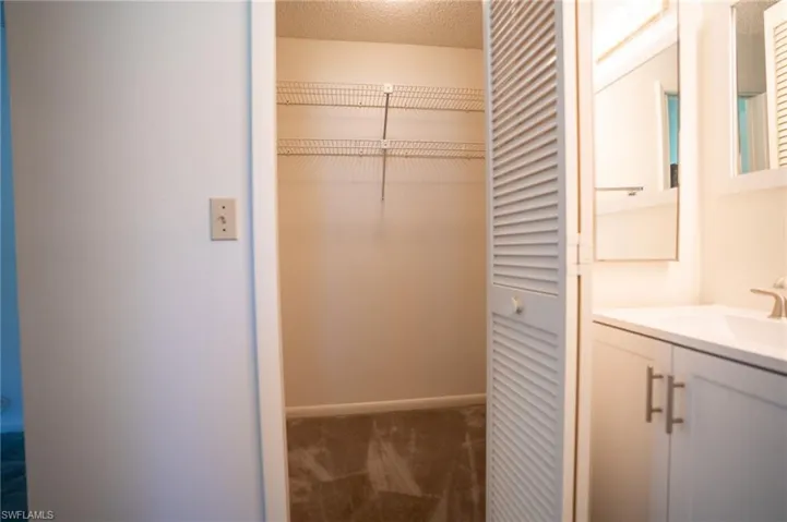 Virtually Staged Primary Bedroom with light colored carpet, ensuite bath, and ceiling fan