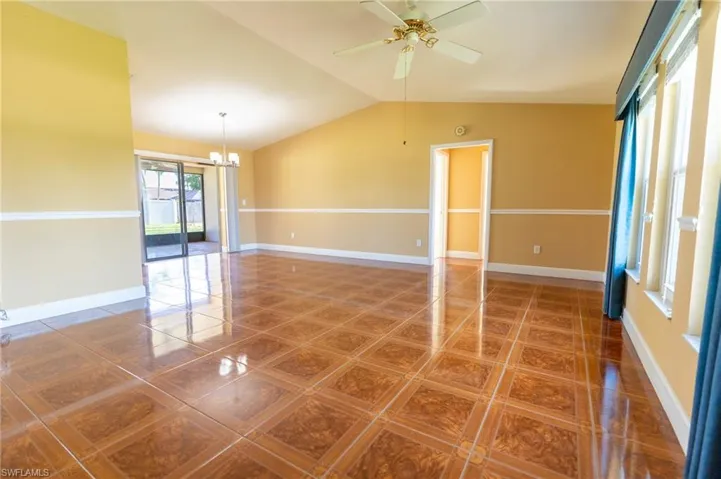 Living Room with lofted ceiling, a chandelier, a ceiling fan, and tile patterned floors