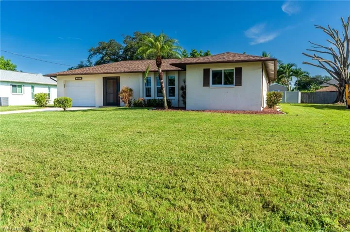 Ranch-style house featuring stucco siding, a front lawn, concrete driveway, and an attached garage