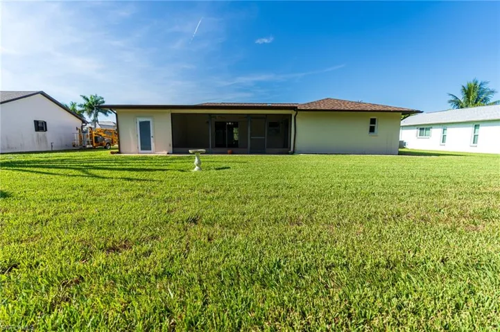 Back of house featuring a lawn, a sunroom, and stucco siding