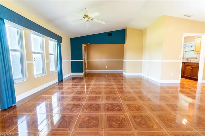 Living Room featuring vaulted ceiling, light tile patterned flooring, and a ceiling fan