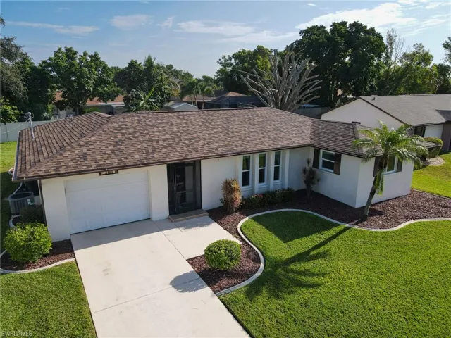 Ranch-style home with roof with shingles, an attached garage, concrete driveway, stucco siding, and a front lawn