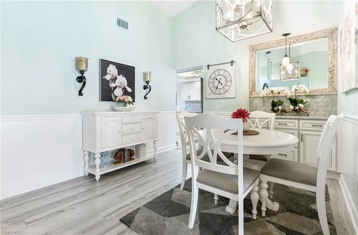 Dining room featuring high vaulted ceiling, a notable chandelier, and light hardwood / wood-style floors