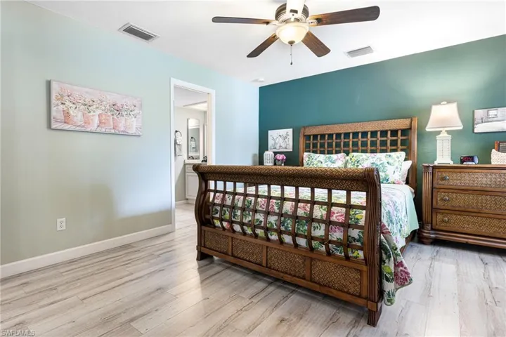 Bedroom with ensuite bath, ceiling fan, and hardwood / wood-style floors