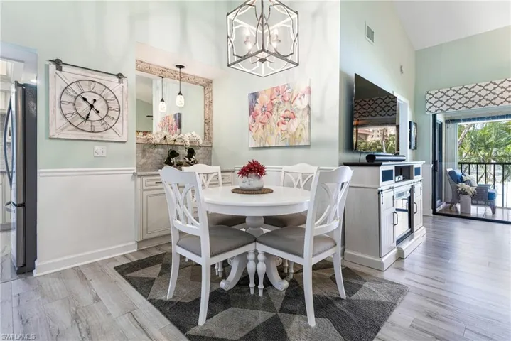 Dining area featuring high vaulted ceiling, light hardwood / wood-style flooring, and a notable chandelier