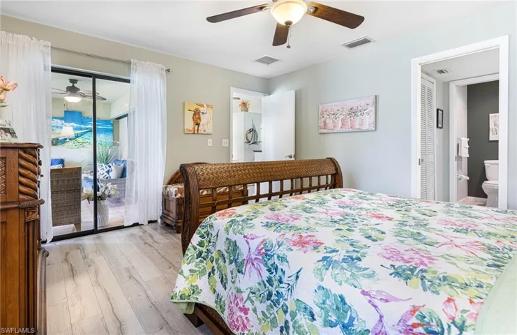 Bedroom with ensuite bathroom, access to outside, ceiling fan, and light hardwood / wood-style floors