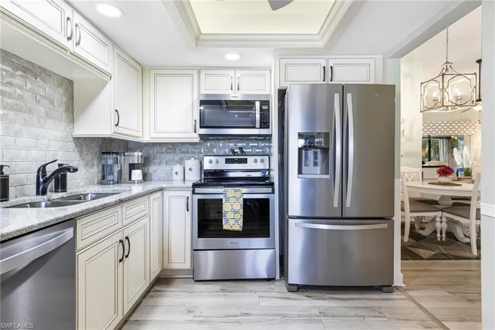 Kitchen featuring sink, light hardwood / wood-style flooring, light stone countertops, and stainless steel appliances