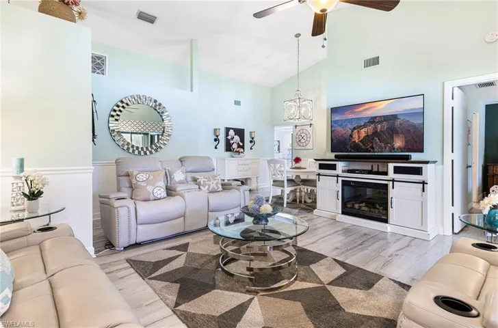 Living room with light hardwood / wood-style floors, ceiling fan, and high vaulted ceiling