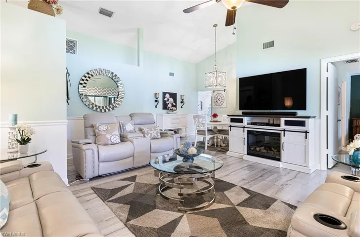 Living room featuring high vaulted ceiling, light wood-type flooring, and ceiling fan
