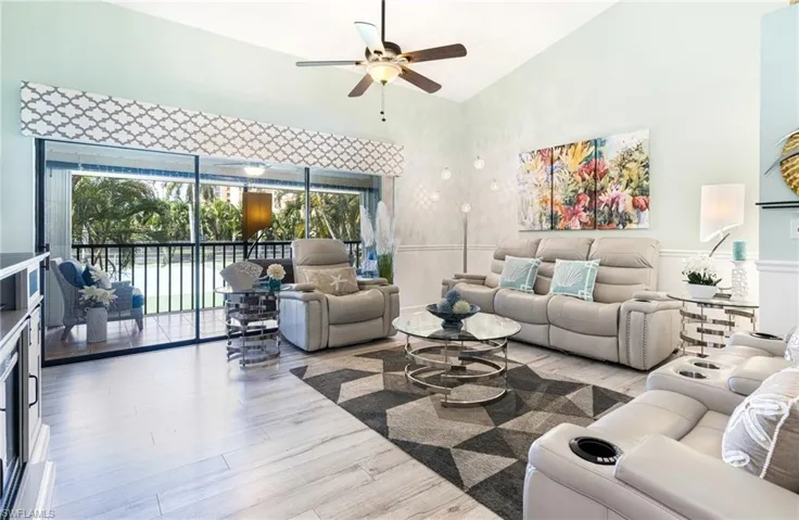 Living room with plenty of natural light, high vaulted ceiling, ceiling fan, and hardwood / wood-style floors