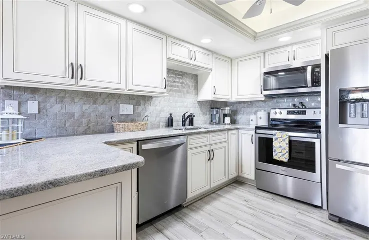 Kitchen featuring ceiling fan, crown molding, light wood-type flooring, appliances with stainless steel finishes, and backsplash