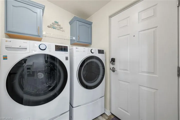 Washroom featuring wood-type flooring, cabinets, and washing machine and clothes dryer
