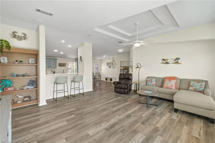 Living room featuring a tray ceiling, hardwood / wood-style flooring, and ceiling fan