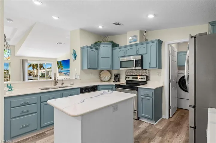 Kitchen featuring light hardwood / wood-style floors, a center island, sink, lofted ceiling, and appliances with stainless steel finishes