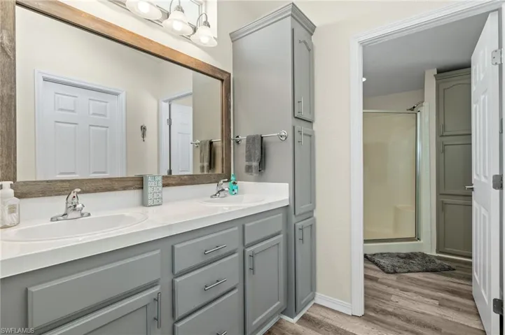 Bathroom with hardwood / wood-style floors, double sink vanity, and an enclosed shower
