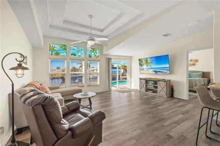Living room featuring ceiling fan, a tray ceiling, and hardwood / wood-style floors