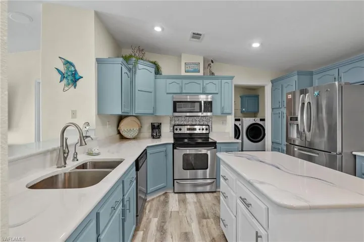 Kitchen featuring appliances with stainless steel finishes, lofted ceiling, blue cabinets, and light hardwood / wood-style flooring