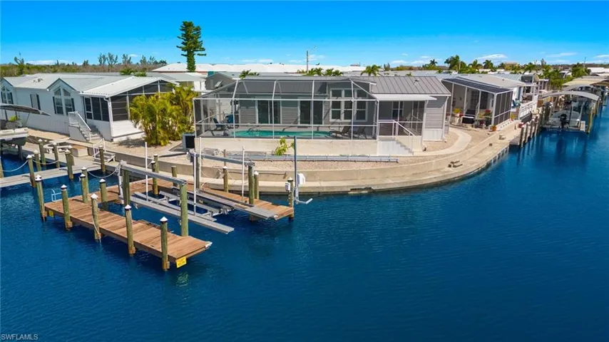 View of dock with glass enclosure, a water view, and a patio area