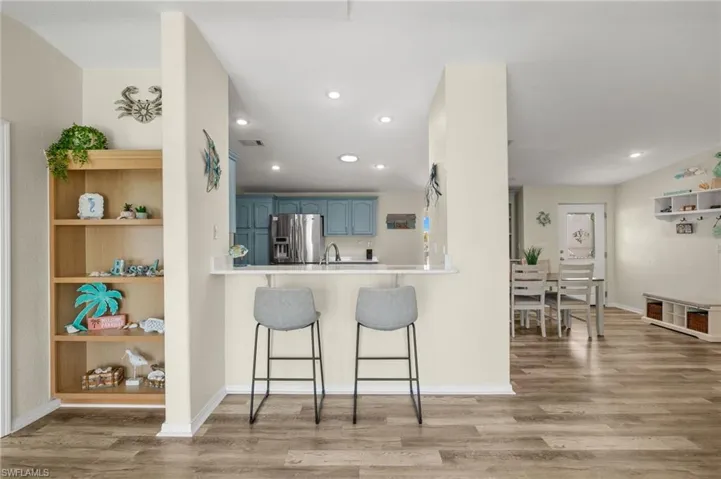 Kitchen featuring stainless steel fridge with ice dispenser, blue cabinets, a breakfast bar area, and hardwood / wood-style flooring