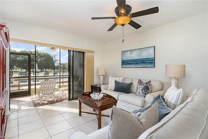 Tiled living room featuring ceiling fan and lots of natural light.