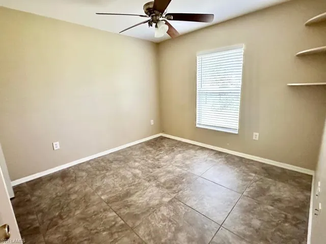 Empty room featuring a ceiling fan and baseboards