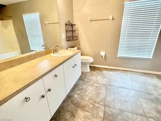 Full bath featuring vanity, light tile patterned floors, and a shower
