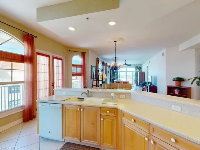 Kitchen with dishwasher, light tile patterned floors, sink, and an inviting chandelier